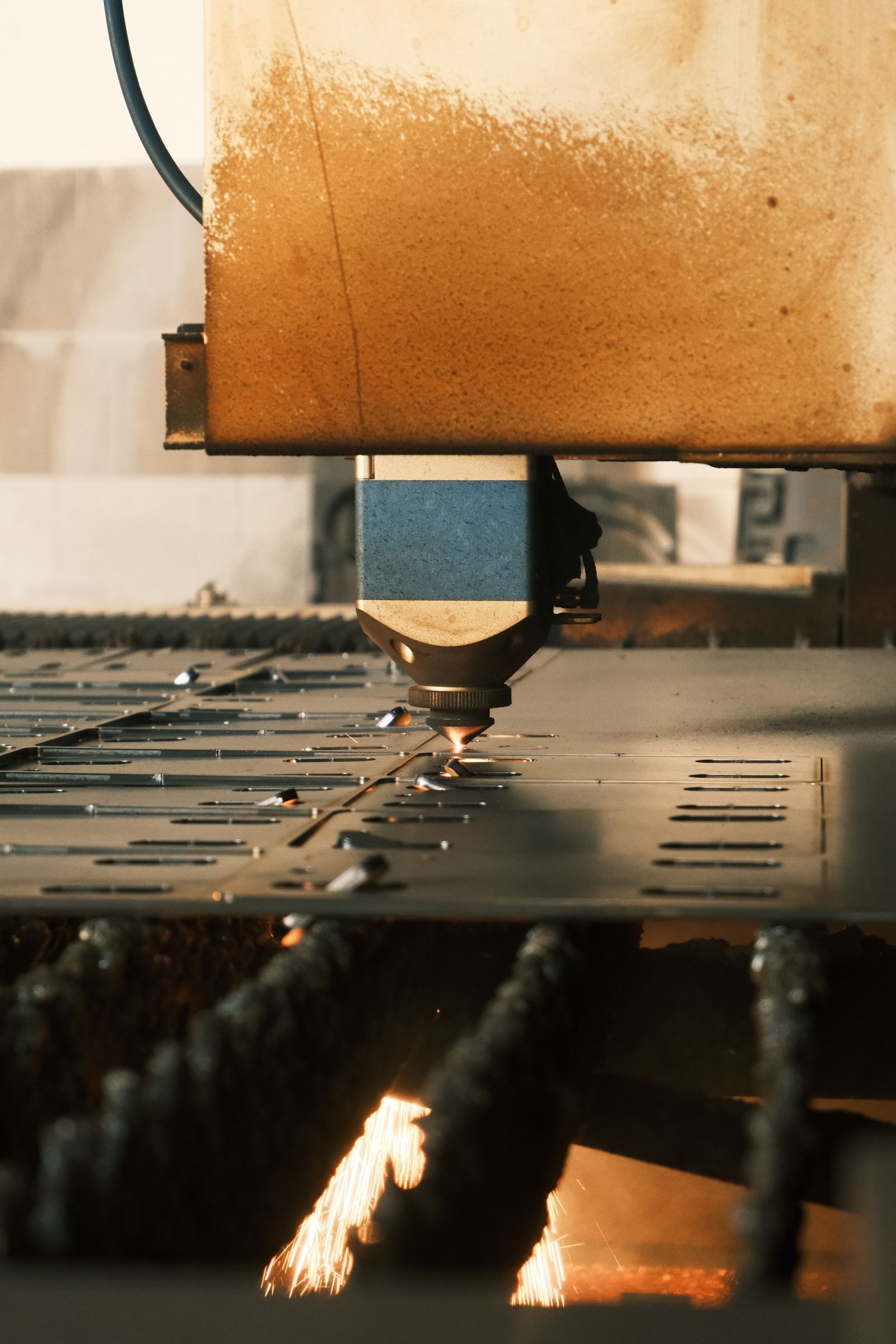 Đầu cắt laser đang cắt chi tiết trên tấm kim loại